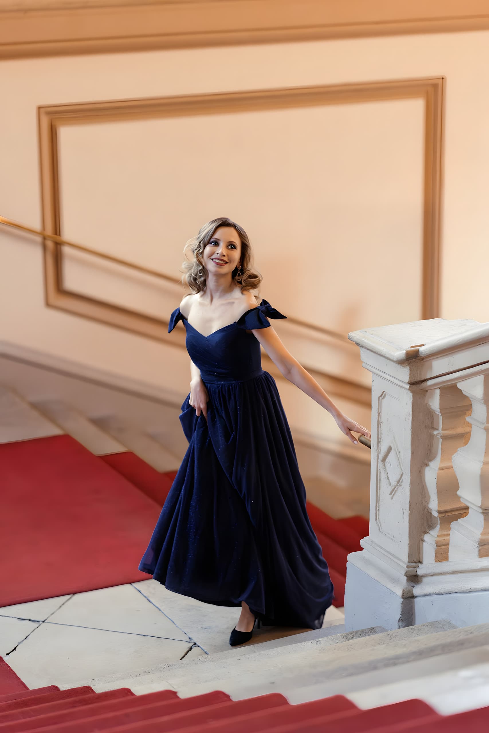 Ball guest in a navy evening gown on the grand staircase