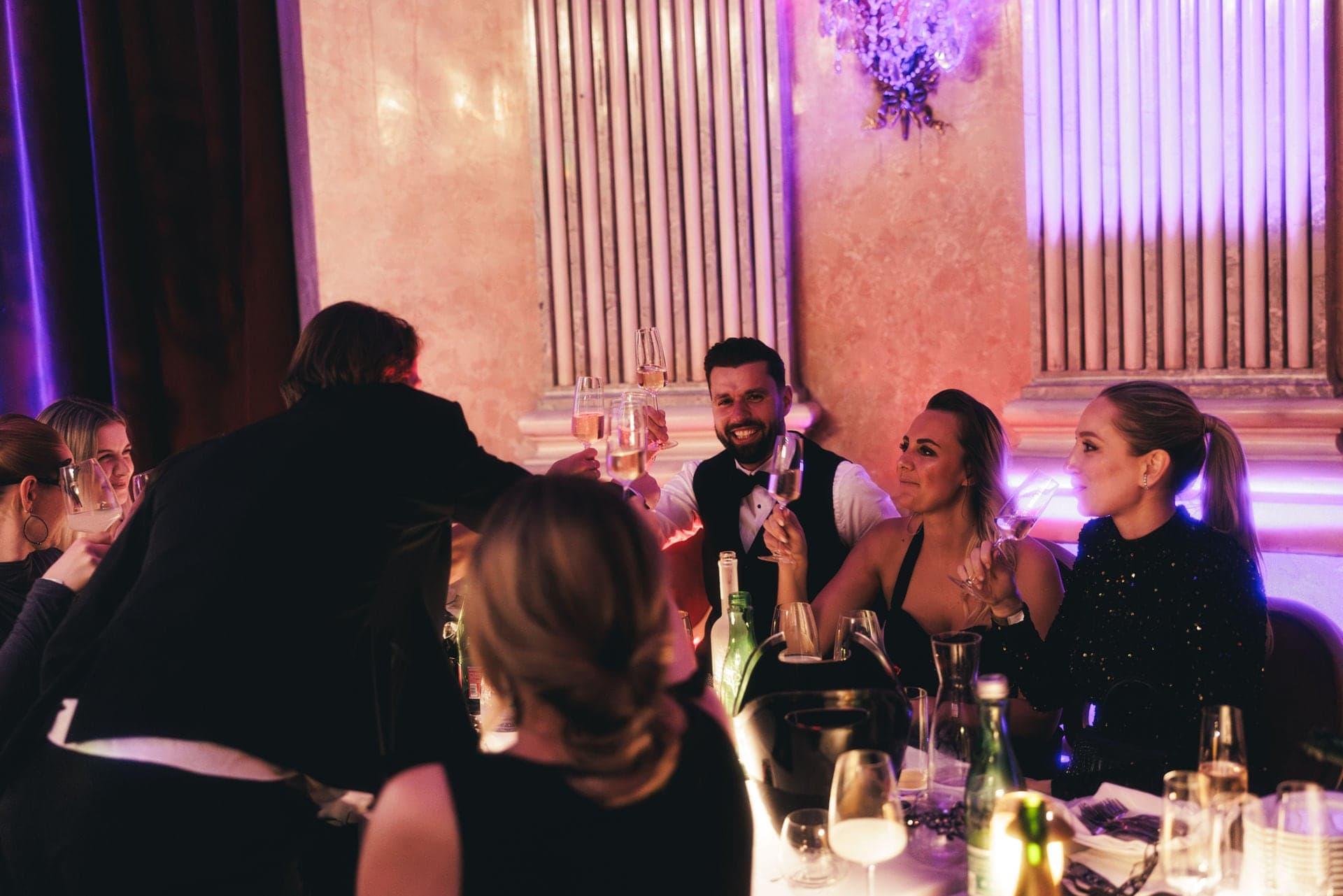 Ball guests talking at their table and raising glasses of sparkling wine