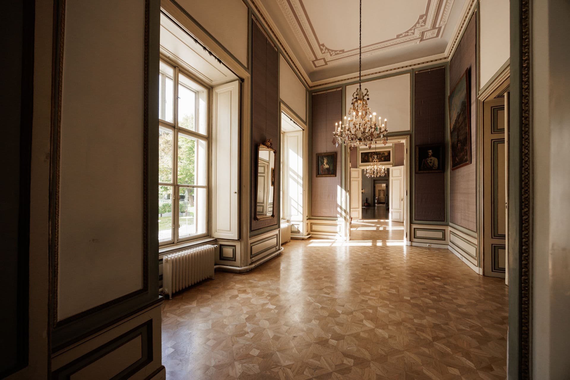 Empty salon with parquet floor, chandelier and tall double doors